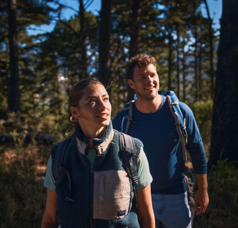 Two hikers look into the forest and smile