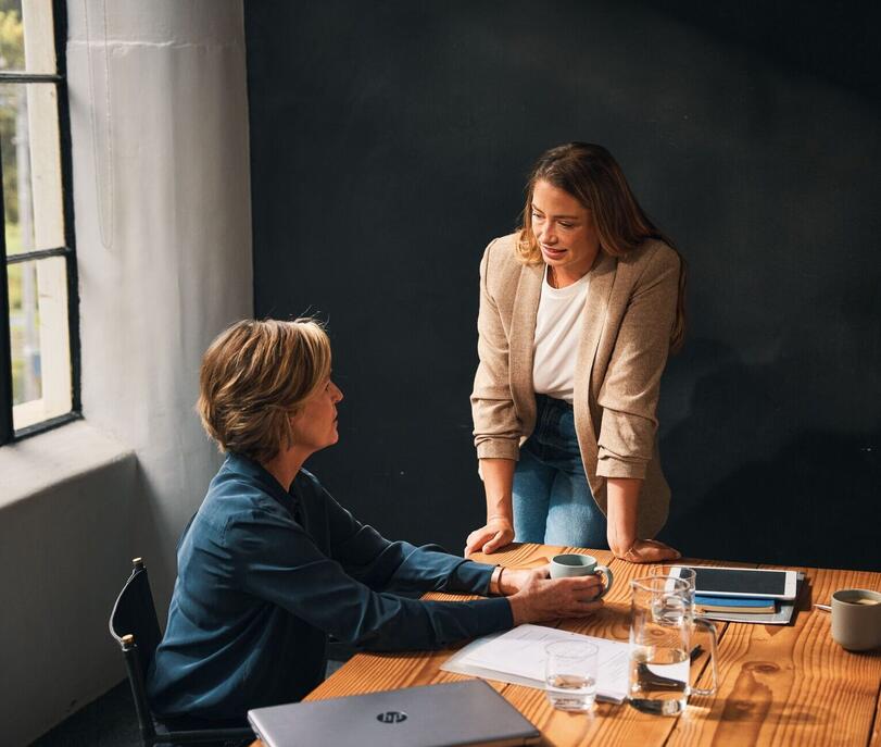 Zwei Frauen diskutieren am Bürotisch